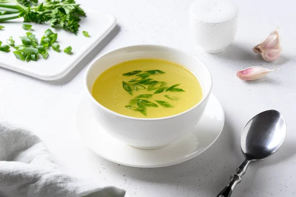 Brodo di pollo con cipolla verde in ciotola bianca sul tavolo bianco. Copia spazio. — Foto Stock