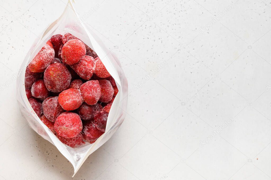 Frozen strawberries in plastic packet on white background. View from above. Copy space. Vitamins. Vegetarian, vegan food.