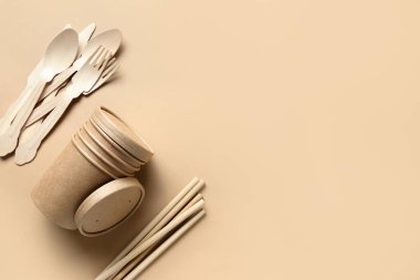 Çevre dostu tek kullanımlık bardaklar, kaşıklar, çatallar, bej üzerine bambu pipetler. Sürdürülebilir yaşam tarzı. Sıfır kayıp. Kirlilik ortamı. Metin için boşluk.