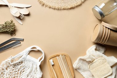 Yenilenebilir bireysel nesneler, bambu ya da metal pipetler, tek kullanımlık bardaklar ve tahta kaşıklar, çatallar, bej üzerine diş fırçası. Sıfır kayıp. Kirlilik ortamı. Üst görünüm.