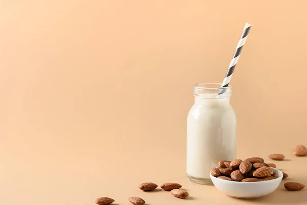 Almond milk in glass bottle on beige background. Healthy vegan milk replacer. Lack of cholesterol. Space for text.