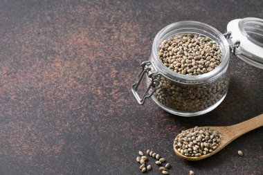 Cam kavanozdaki kenevir tohumları kahverengi üzerine. Vejetaryenlerin yerine kullanışlı protein. Boşluğu kopyala.