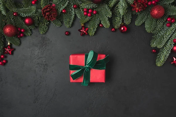 Vánoční rám s červeným dárkem a dekorem, jedlové větve na černém pozadí. Vánoce. Pohled shora, plochá poloha. — Stock fotografie
