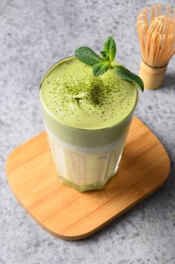 Bir bardak dalgona buzlu kibrit çayı ve gri üzerine bambu..