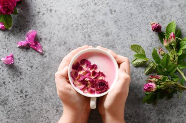 Güllü ay sütü gri ellerde. Ayurveda sıcak içeceği. Uykusuzluk durumunda güzel..