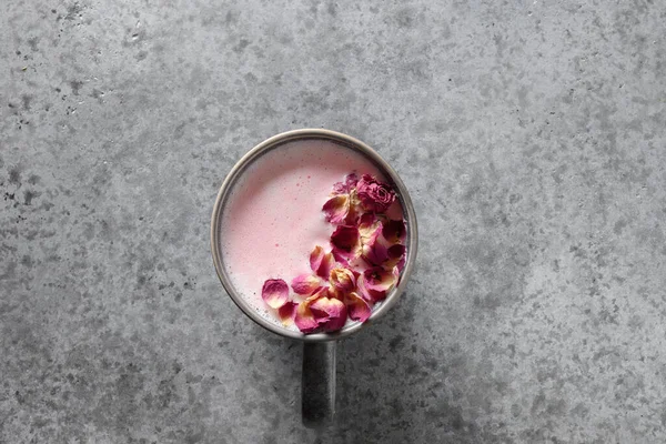 One cup of rose moon milk on grey background. Top view. Copy space.