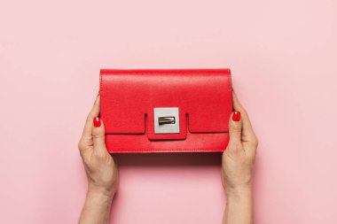 Kırmızı manikürlü kadın elleri pembeye tutunuyor. Yukarıdan görüntüle.