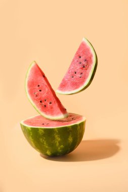 Bej kağıtların altında dilimlenmiş olgun karpuz uçuyor. Dikey yaratıcı kompozisyon.