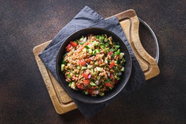 Mevsimlik sebzelerle, domateslerle, salatalıklarla, koyu arka planda yeşilliklerle kaplı tahıl gevreği salatası. Üst görünüm.