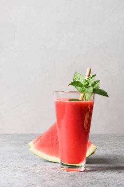 Gri arkaplanda bir bardak karpuz kokteyli, nane şekeri. Kapatın. Dikey.