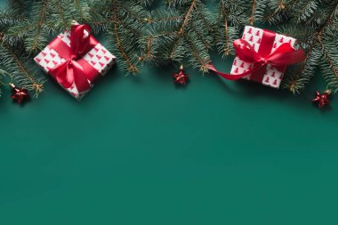 Kırmızı hediyeli Noel çerçevesi, yeşil arkaplanlı köknar dalları ve fotokopi alanı. Xmas tebrik kartı. Yukarıdan bak, düz yat.
