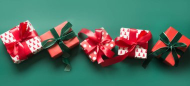 Yeşil arka planda kırmızı ve yeşil desenli birçok Noel hediyesinin afişi. Xmas tatil hediyeleri. 