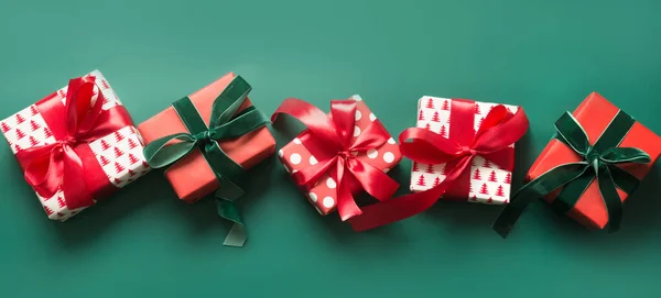 Banner of many Christmas gifts in red and green decor on green background. Xmas holiday presents.