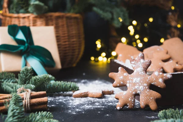 Composición de vacaciones de sabrosas galletas caseras, cesta de regalo, regalo y guirnalda en negro. —  Fotos de Stock