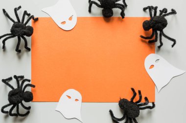 Gri ve turuncu renkli hayalet ve siyah örümceklerle cadılar bayramı davetiyesi boş. Düz konum, üst görünüm, kopyalama alanı.
