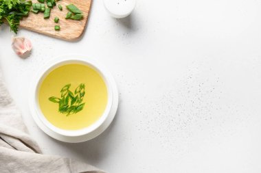 Beyaz masadaki beyaz kasede yeşil soğanlı tavuk çorbası. Uzayı kopyala Üst görünüm.