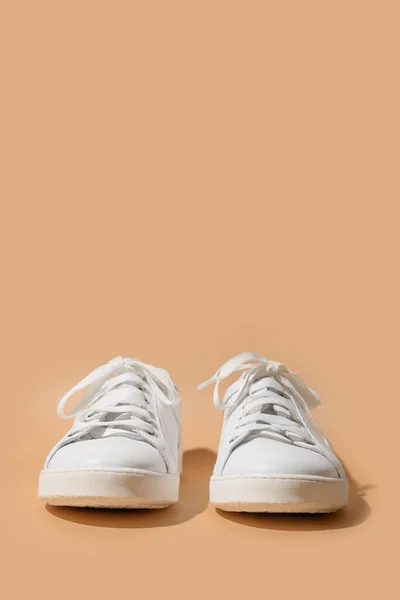 Weiße weibliche Gummischuhe auf beigem Hintergrund. — Stockfoto