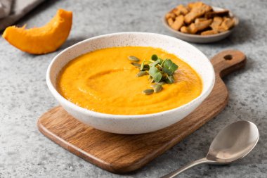 Lezzetli balkabağı çorbası garnitür mikro yeşillikler ve gri malzemeli krakerler. Kapat..