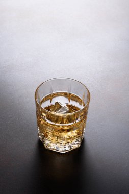 Koyu kahverengi arka planda buz küplü bir viski..