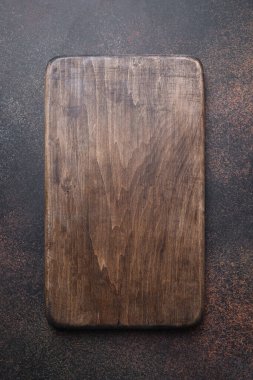 Koyu kahverengi mutfak arka planında tahta kesme tahtası. Üst görünüm düzlüğü.