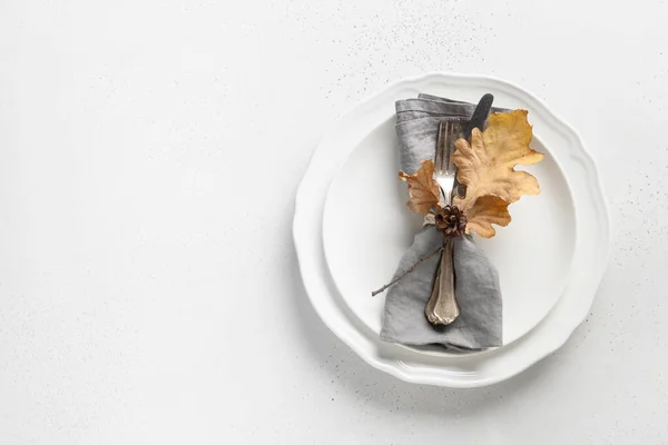 Elegant fall table setting with autumn leaves and white plate on white table. View from above. Space for text.