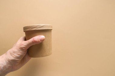 Kadınların elindeki tek kullanımlık karton çorba bardağının arka planındaki kahverengi kağıtta fotokopi alanı var. Ekolojik bireysel paket.