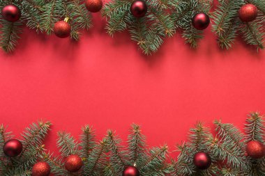 Her zaman yeşil köknar dalları olan Noel çerçevesi, kırmızı arka planda kırmızı toplar. Tatil tebrik kartı. Mutlu yıllar..