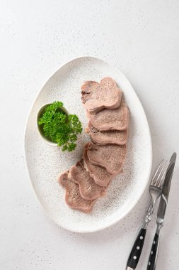 Beyaz bir tabakta dilimlenmiş sığır dili lezzeti. Doğal yaban turpu soslu güzel bir klasik. Yukarıdan bak. Dikey biçim.