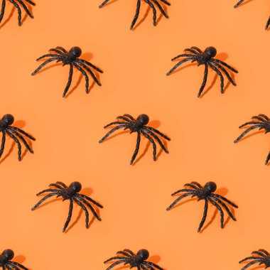 Cadılar Bayramı siyah örümceklerinin kusursuz deseni, turuncu arka planda eğlenceli süslemeler..