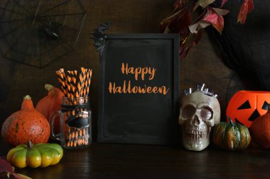 Kafatası, balkabağı, yarasa, ürkütücü örümcekler, şeker kasesi, kabak kafalı balkabağı kabağı kabağı kabağı. Tahtadaki yazı - Mutlu Cadılar Bayramı.