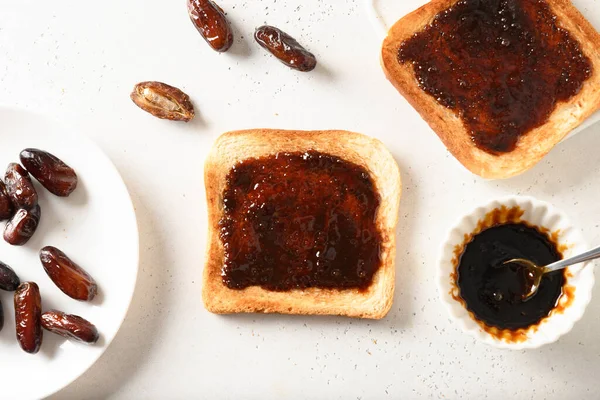 Fresh crispy toasts with dates syrup without sugar on white table. View from above. Healthy breakfast without sugar.
