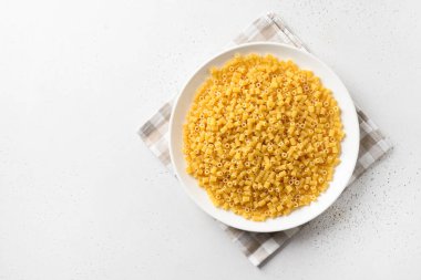 Beyaz arka planda beyaz tabakta çiğ ditalini makarna. Yukarıdan bak. Boşluğu kopyala.