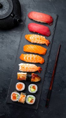 Suşi ruloları özenle tek tip kesiliyor, mükemmel baharatlı pirinç ve yosunlara sarılmış taze balık ve sebze dolgularını ortaya çıkarıyor, ve lezzetli bir doku kontrastı sunuyor.