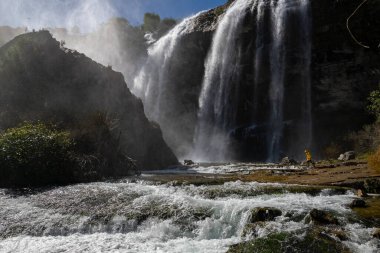 Tortum 'daki büyük şelaleye doğru yürüyen bir adam. Dünyanın güzelliğini ve vahşi yaşamını keşfedin. Büyük şelaledeki adam