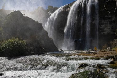 Tortum 'daki büyük şelaleye doğru yürüyen bir adam. Dünyanın güzelliğini ve vahşi yaşamını keşfedin. Büyük şelaledeki adam