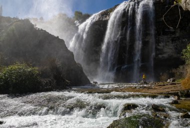 Türkiye 'deki Tortum Şelalesi' ne bakan maceraperest. Türkiye 'deki Tortum şelalesinde dinlenen sarı ceketli bir turist. Türkiye 'nin Erzurum kentindeki Tortum Şelalesinin manzara görüntüsü