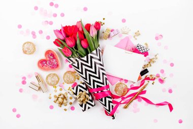 Pembe ve altın tarz Masası çiçekler ile. Siyah ve beyaz şık ambalaj kağıdı, hediyeler, kozmetik ve beyaz zemin üzerine konfeti ile kadın Aksesuarları Pembe Laleler