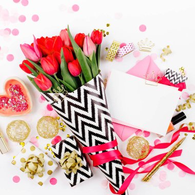 Pembe ve altın tarz Masası çiçekler ile. Siyah ve beyaz şık ambalaj kağıdı, hediyeler, kozmetik ve beyaz zemin üzerine konfeti ile kadın Aksesuarları Pembe Laleler