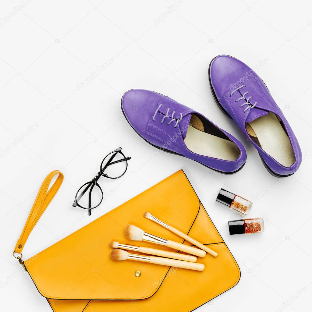 Flat lay of female fashion accessories, shoes, makeup products and handbag on orange colors. Beauty and fashion concept