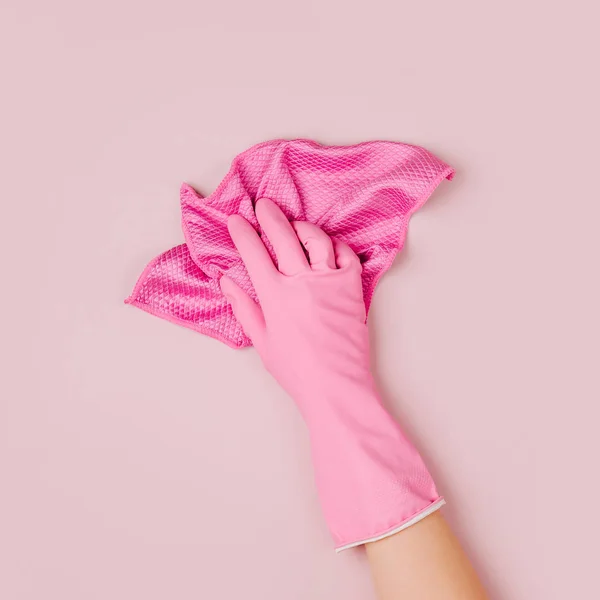 Female hand cleaning on pale pink  background. Cleaning or housekeeping concept background. Copy space.  Flat lay, Top view.