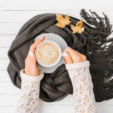 Kadınların elleri bir fincan kahve eşarp ahşap arka plan üzerinde sarılı tutun. Sonbahar ya da kış kavramı. düz yatıyordu, en iyi görünümü