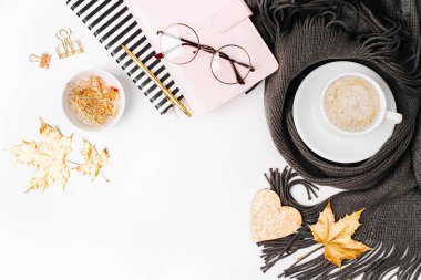 Altın akçaağaç yaprakları, defter, kahve fincanı ile çalışma alanı eşarp, gözlük sarılmış. Şık ofis masası. Sonbahar ya da kış kavramı. Düz yatıyordu, en iyi görünümü