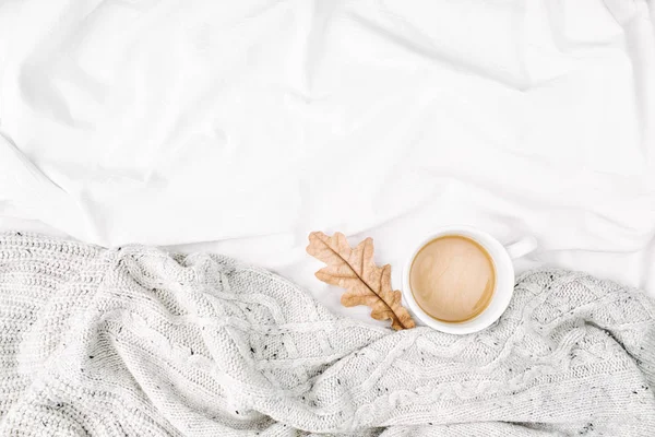 Cup of coffee on bed with warm plaid. Copy space. Flat lay, top view