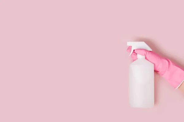 Female hand cleaning on pale pink  background. Cleaning or housekeeping concept background. Copy space.  Flat lay, Top view.