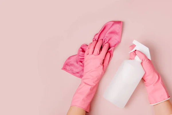 Female hands cleaning on pale pink  background. Cleaning or housekeeping concept background. Copy space.  Flat lay, Top view.