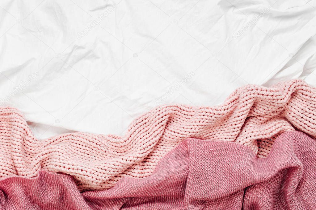 Top view of pink knitted plaid on bedding sheet