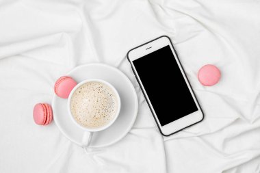 bir fincan kahve ve Smartphone yatakta üstten görünüm.