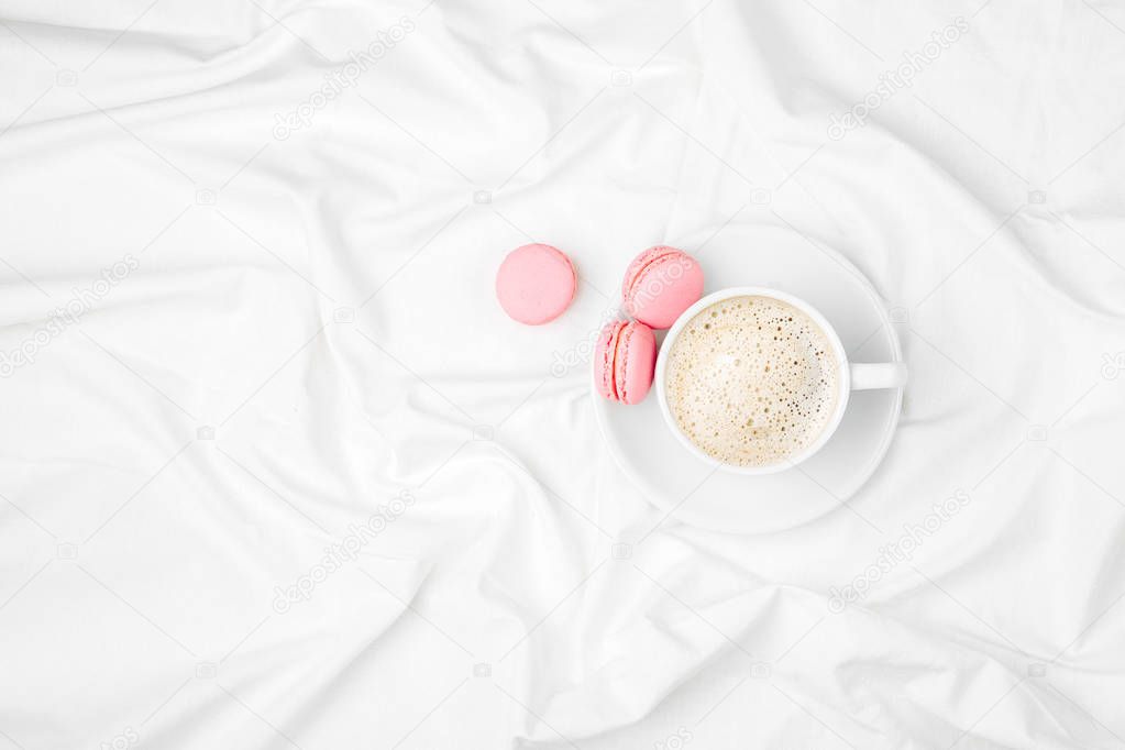 top view of Cup of coffee and macaroons on bed 
