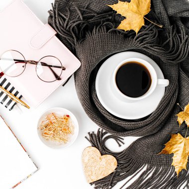 Çalışma alanı boş oyun kağıdı, kahve fincanı ile defter ile eşarp, gözlük sarılmış. Şık ofis masası. Sonbahar ya da kış kavramı. Düz yatıyordu, en iyi görünümü