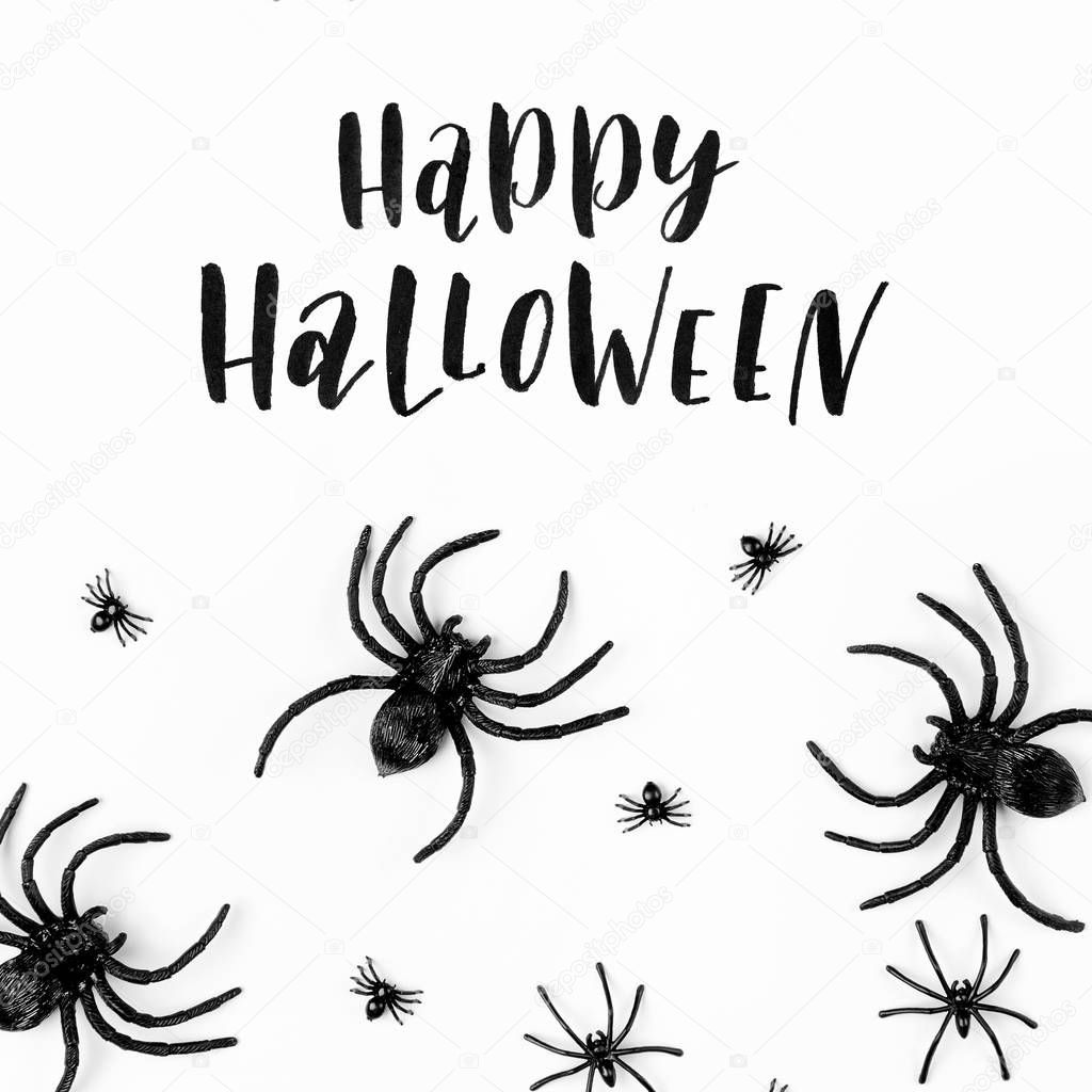 Halloween background with spiders on white surface and lettering Happy Halloween